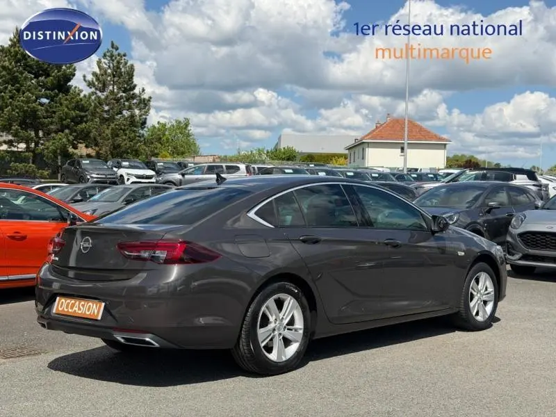 Opel Insignia Grand Sport brun carbone vue 3/4 arrière droit, jantes alu et feux arrière LED visibles.