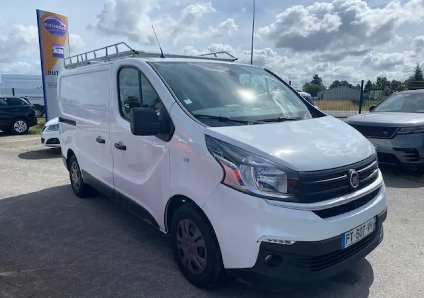 Fourgon Fiat Talento blanc vu en 3/4 avant droit avec galerie de toit et porte coulissante côté droit.