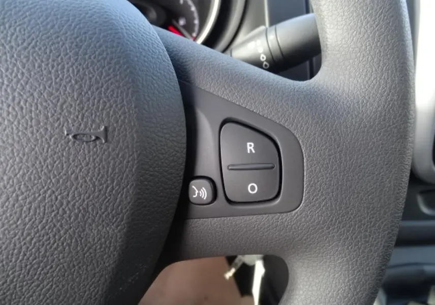 Gros plan sur les commandes du volant du FIAT Talento Fourgon blanc, version 2020, avec boutons de réglage vocal et radio.