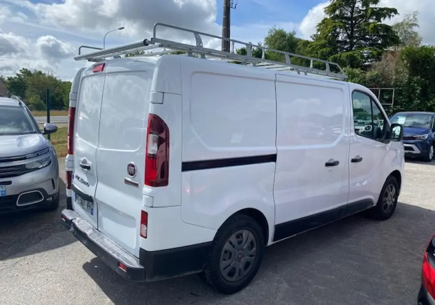 Fiat Talento Fourgon blanc vu en 3/4 arrière droit avec galerie de toit et portes arrière tôlées ouvertes à 180°.