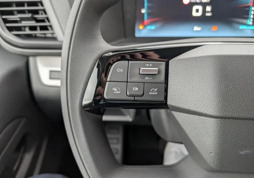 Gros plan sur les commandes gauche du volant gris du Citroën Jumpy XL 2025 avec écran numérique en arrière-plan.