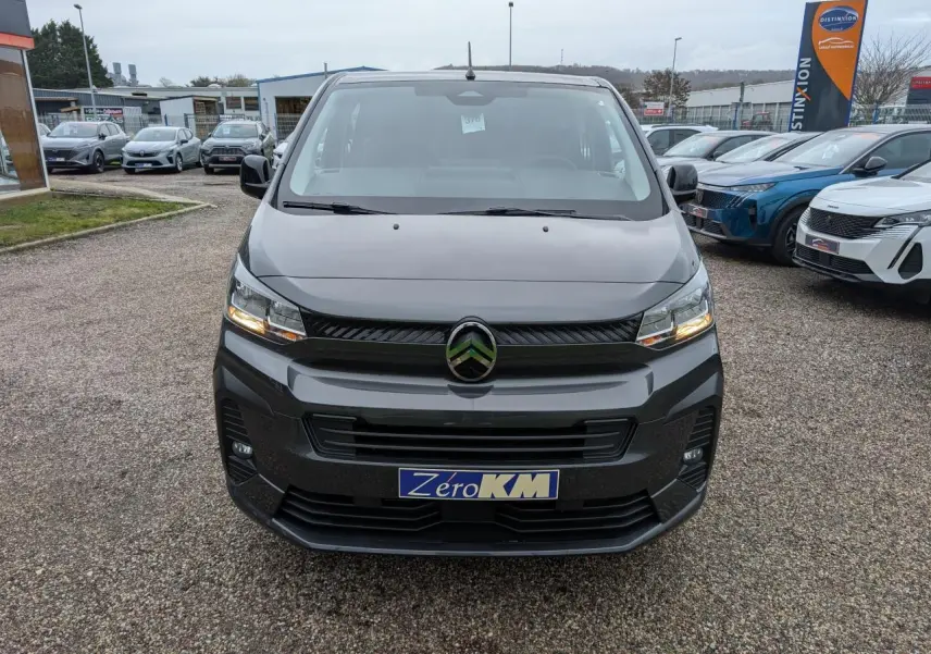 Vue avant d’un Citroën Jumpy XL gris avec phares allumés sur un parking extérieur.