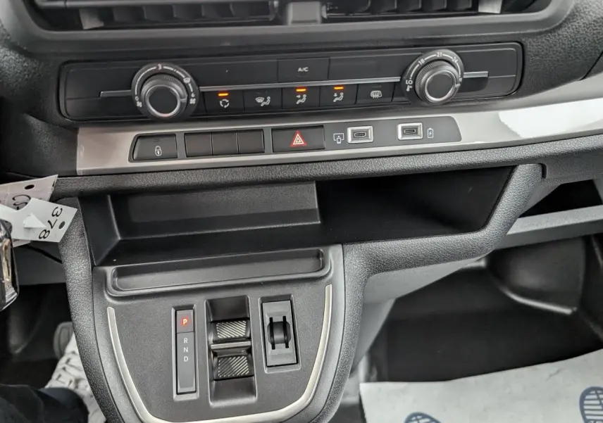 Vue rapprochée de la console centrale noire du Citroën Jumpy gris avec commandes de climatisation et boîte automatique.
