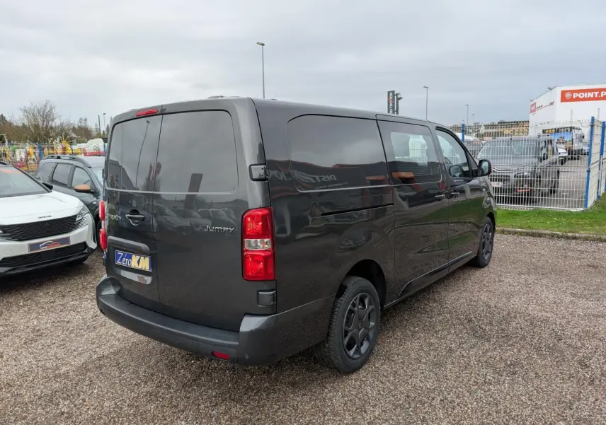 Vue 3/4 arrière droite d’un Citroën Jumpy XL gris métallisé avec boucliers teintés et vitres arrière surteintées.