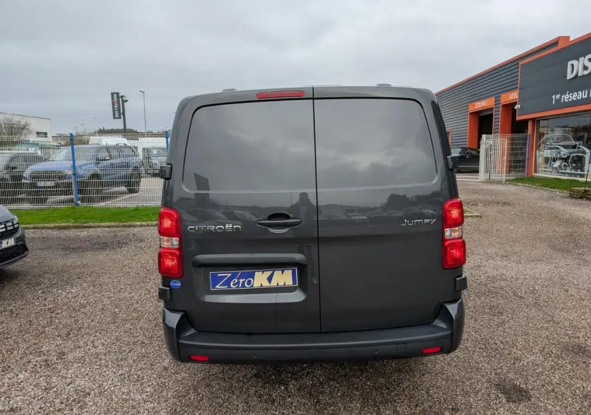 Vue arrière d’un Citroën Jumpy gris 2025 avec portes battantes et bouclier arrière demi-peint noir.