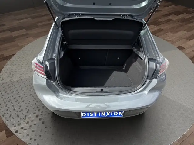 Coffre ouvert vu de l'arrière d'une Peugeot 208 gris foncé 2024, montrant l'espace de chargement et les feux arrière LED.