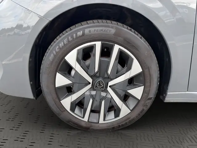 Gros plan sur la roue avant droite d’une Peugeot 208 gris foncé avec jante en alliage au design géométrique.