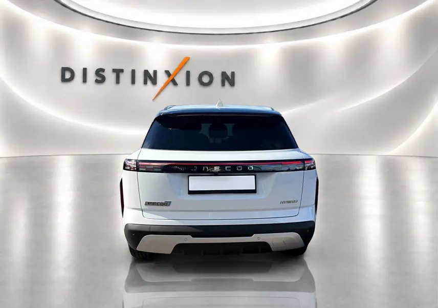 Vue arrière du SUV JAECOO J7 blanc kaki avec feux arrière LED et toit panoramique en verre dans un showroom lumineux.