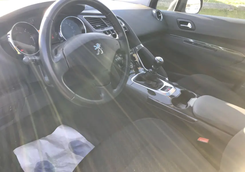 Intérieur noir de Peugeot 3008 Business 2015 vu côté conducteur, volant et levier de vitesse manuelle visibles.