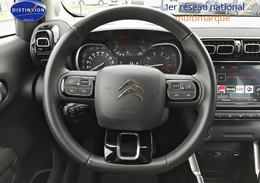 Vue centrée sur le volant noir du Citroën C3 Aircross 2022, avec tableau de bord et écran tactile en arrière-plan.