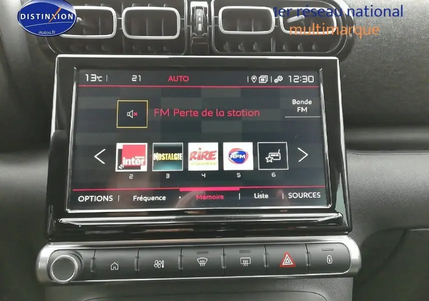Écran tactile central de la Citroën C3 Aircross blanc polar, affichant les stations radio FM avec commandes climatisation en dessous.