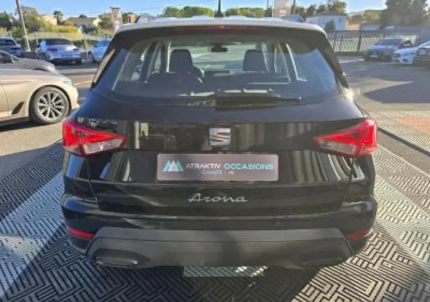 Vue arrière d'un SEAT Arona noir minuit avec toit contrasté et feux arrière rouges en extérieur.