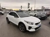 Vue 3/4 avant d’un KIA Xceed blanc 2021 hybride rechargeable, avec jantes noires et toit panoramique visible en concession.