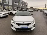 Vue avant d’un KIA Xceed blanc 1.6 GDI 141 Premium hybride rechargeable, garé en extérieur dans un parking urbain.