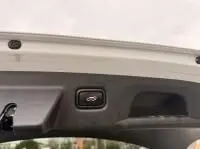 Bouton d'ouverture du coffre sur le hayon intérieur d'une KIA Xceed blanche hybride rechargeable vue de près.