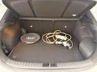 Coffre ouvert d’un KIA Xceed blanc 2021 hybride rechargeable, montrant la prise de recharge et un tapis de coffre noir.