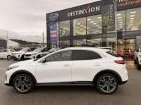 KIA Xceed 1.6 GDI blanc vue de profil côté gauche, hybride rechargeable, devant un showroom avec d’autres véhicules.