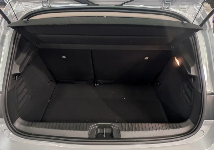 Coffre ouvert vu de l'arrière d'une Renault Clio V gris Rafale, montrant un espace de rangement propre et éclairé.