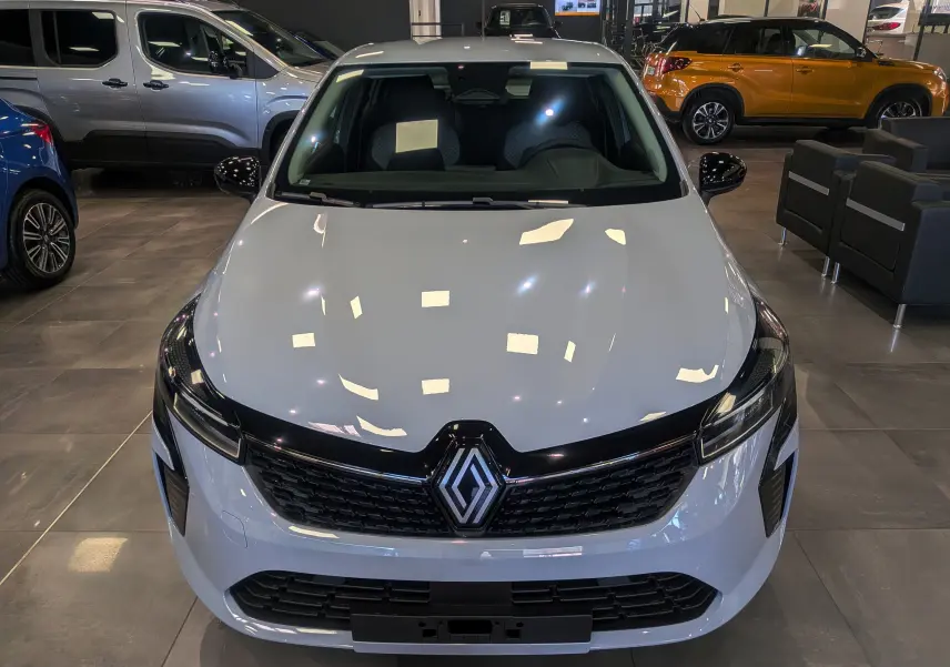 Vue avant d'une Renault Clio V gris Rafale en showroom, avec calandre noire et logo Renault bien visible.