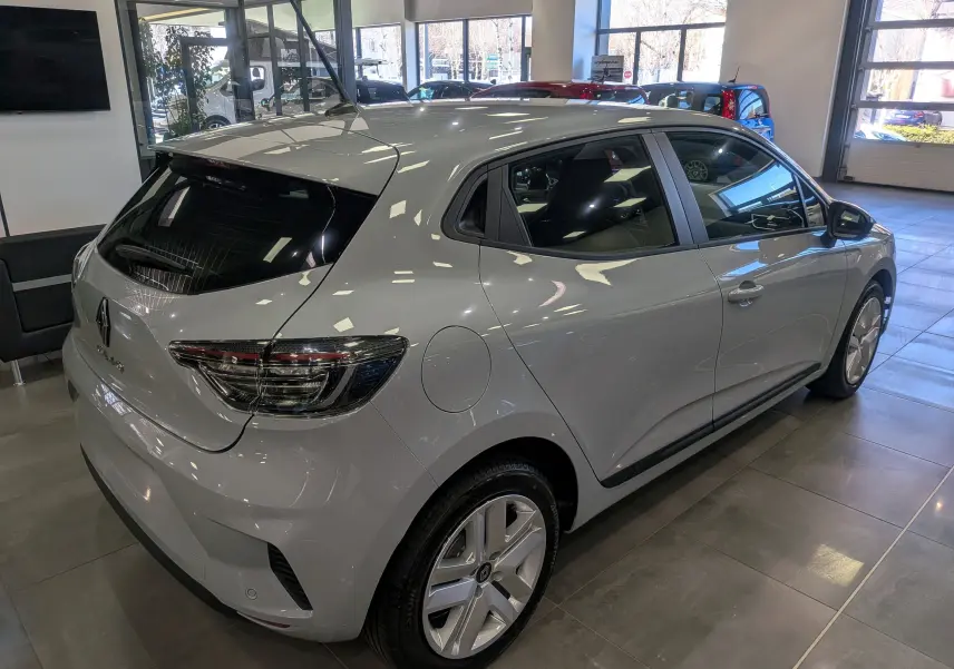 Vue 3/4 arrière droite d'une Renault Clio V gris Rafale en showroom, mettant en valeur ses feux arrière et jantes.