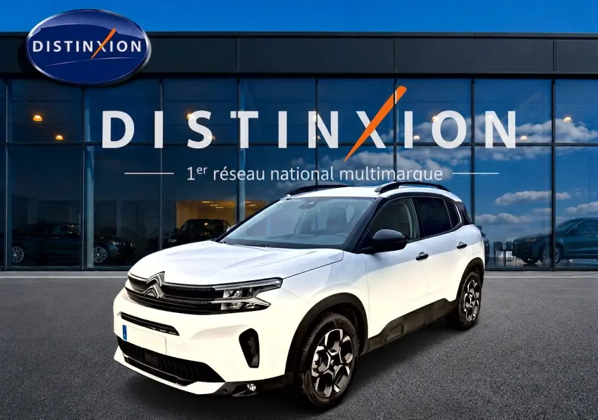 Citroën C5 Aircross blanc vue 3/4 avant droit avec jantes alu et barres de toit noires devant showroom Distinxion.