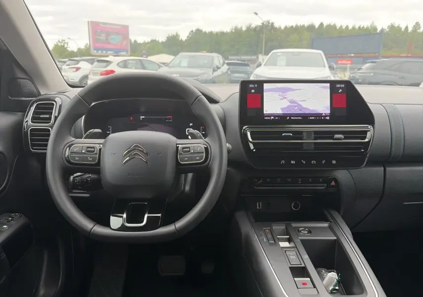 Vue intérieure avant du poste de conduite du Citroën C5 Aircross blanc avec écran tactile et volant multifonction noir.