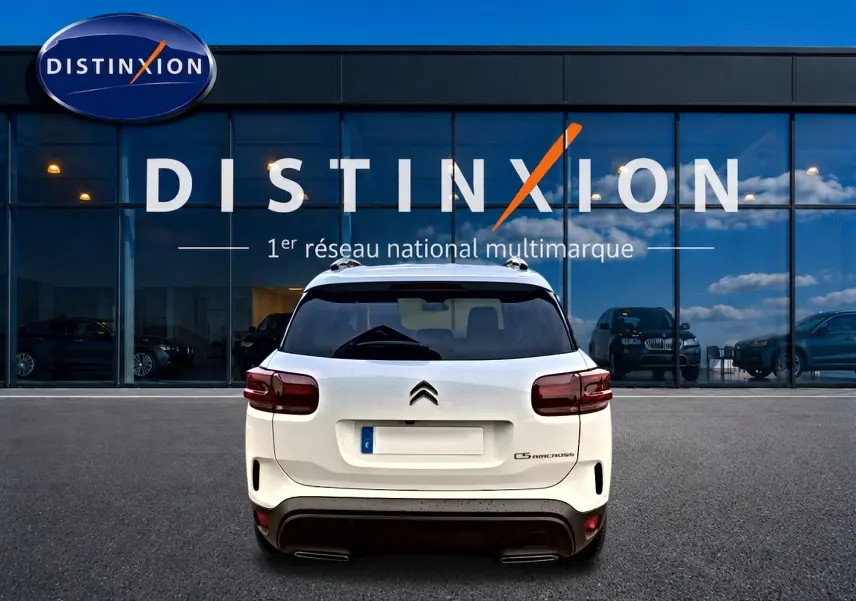 Vue arrière d'un Citroën C5 Aircross blanc 2025 avec barres de toit et feux arrière LED, devant une vitrine Distinxion.