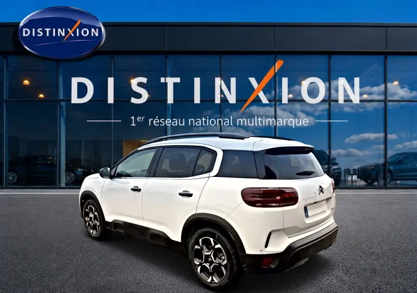 Citroën C5 Aircross blanc vue 3/4 arrière droit, avec toit noir et jantes alliage distinctives, devant showroom Distinxion.