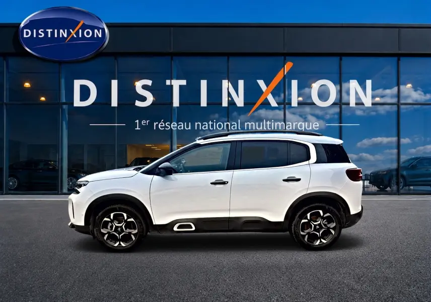 Profil droit du Citroën C5 Aircross blanc 2025 avec jantes alu et barres de toit devant une vitrine Distinxion.