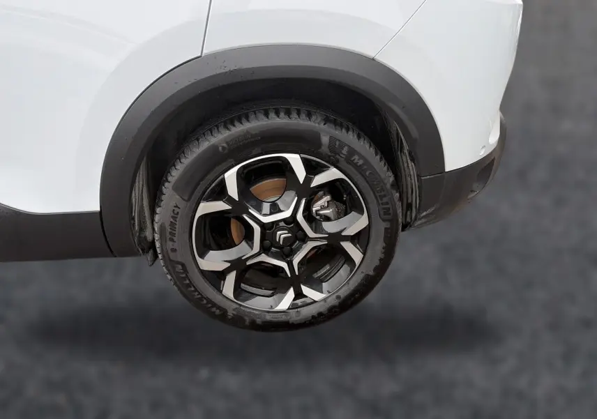 Gros plan sur la roue arrière droite d'un Citroën C5 Aircross blanc avec jante alliage noire et argentée.