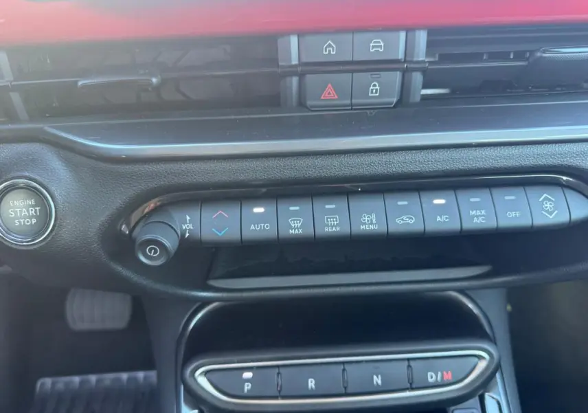 Vue rapprochée de la console centrale du Fiat 600 rouge 2025, montrant les commandes climatisation et boîte auto.