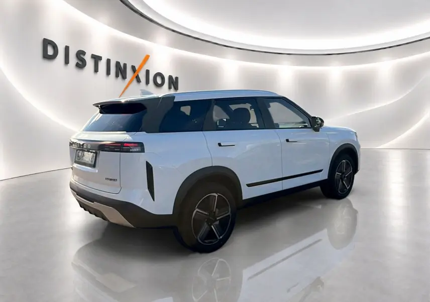 Vue 3/4 arrière droite du SUV JAECOO J7 blanc kaki avec toit noir et jantes alu noires dans un showroom lumineux.