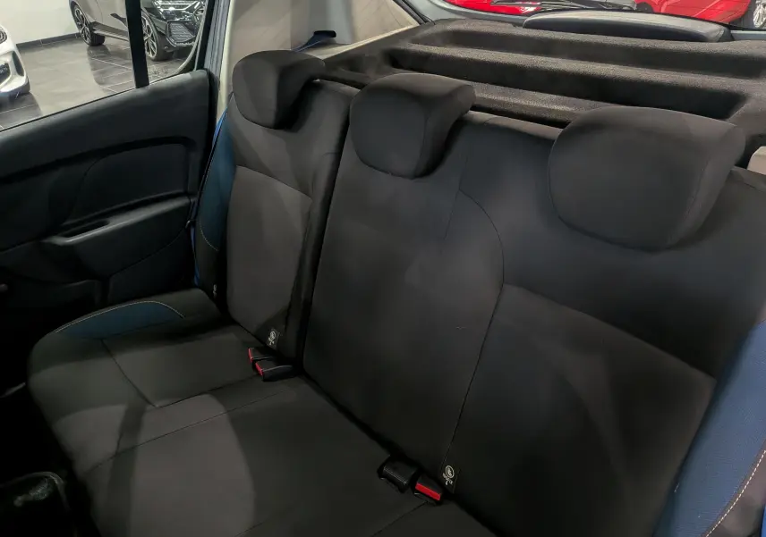 Vue intérieure arrière montrant la banquette noire avec appuie-têtes et détails bleus sur une Dacia Sandero Blanc Glacier 2015.