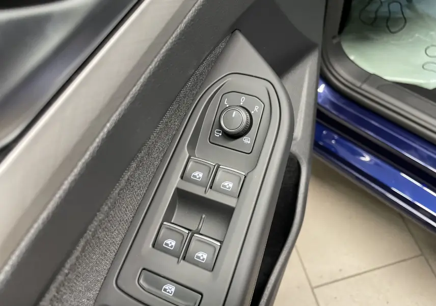Gros plan sur les commandes des vitres et rétroviseurs côté conducteur d'une Volkswagen Golf 2023 bleu Atlantique.