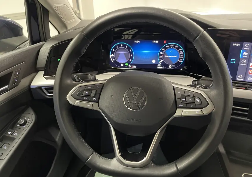 Vue intérieure centrée sur le volant multifonction noir de la Volkswagen Golf 1.0 TSI 110 DSG7 avec tableau de bord numérique.