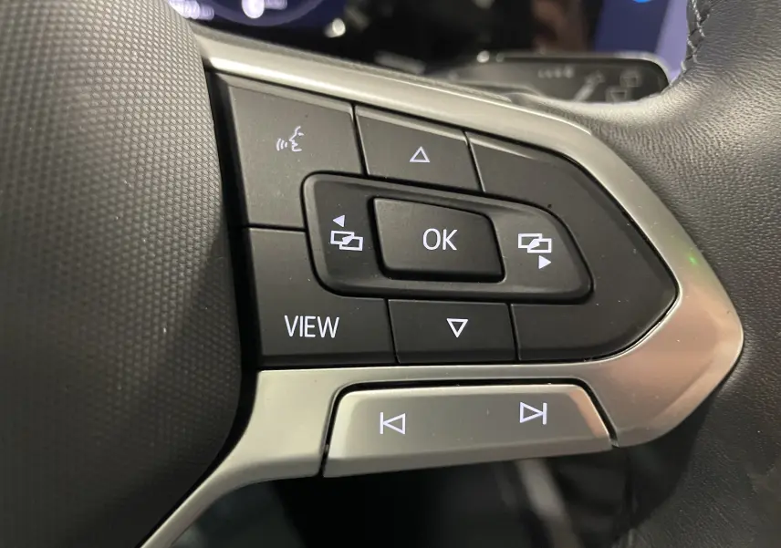 Gros plan sur les commandes au volant côté gauche d'une Volkswagen Golf 2023, boutons noirs et argentés.