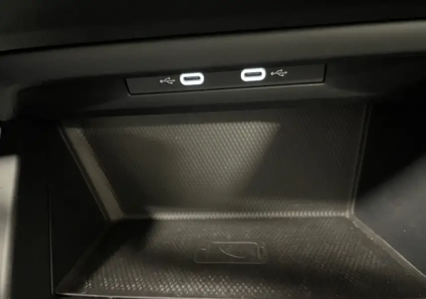 Gros plan sur la zone de recharge sans fil et deux ports USB-C éclairés dans la console centrale d'une Volkswagen Golf Bleu Atlantique 2023.