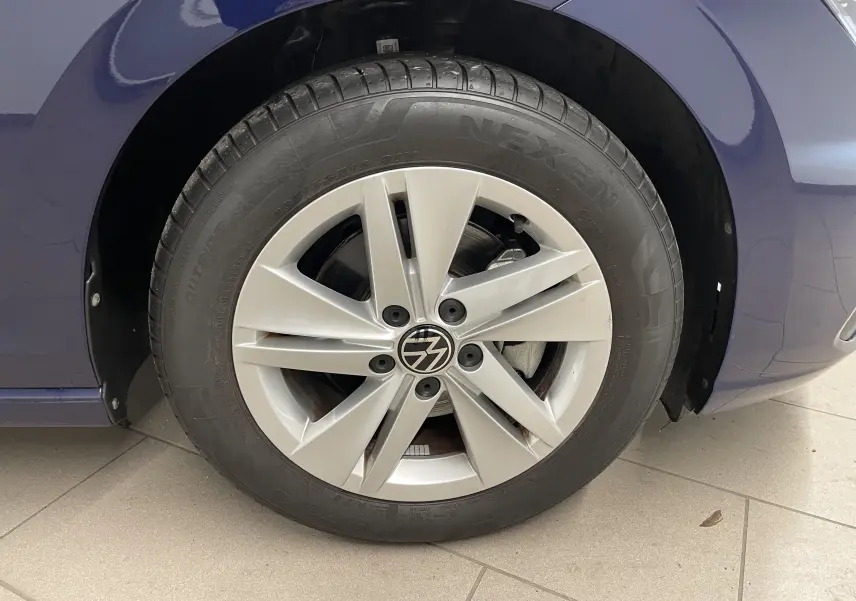 Gros plan sur la roue avant droite d'une Volkswagen Golf 2023 bleu Atlantique avec jante alliage à cinq branches.