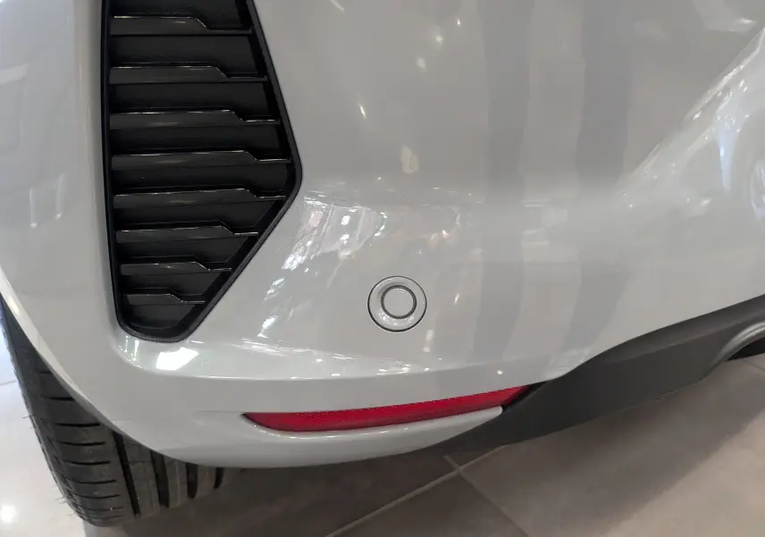 Gros plan sur le pare-chocs arrière gris Rafale de la Renault Clio V avec capteur de recul et feu réfléchissant.