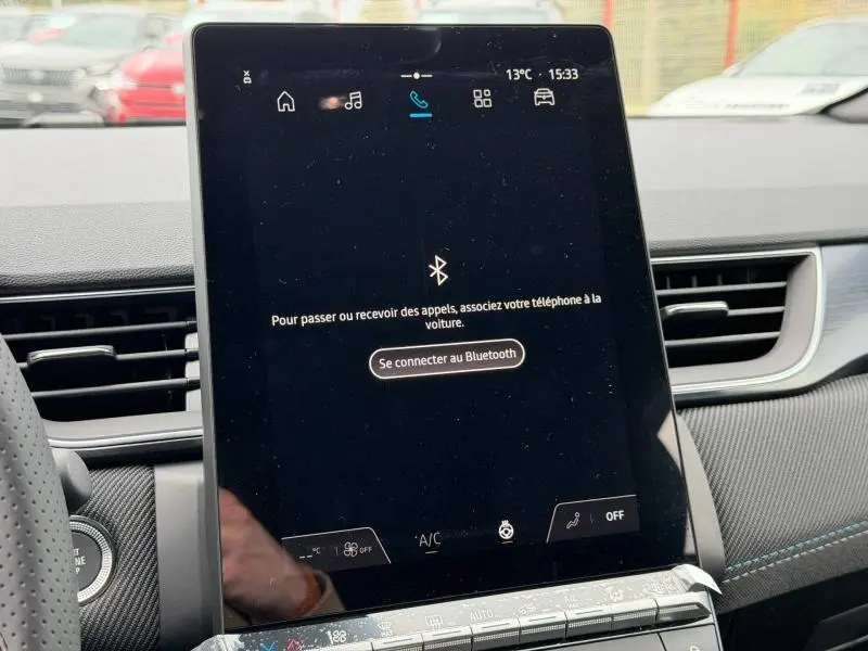 Vue intérieure centrée sur l'écran tactile du tableau de bord du Renault Captur blanc nacré/noir étoile, affichant la connexion Bluetooth.