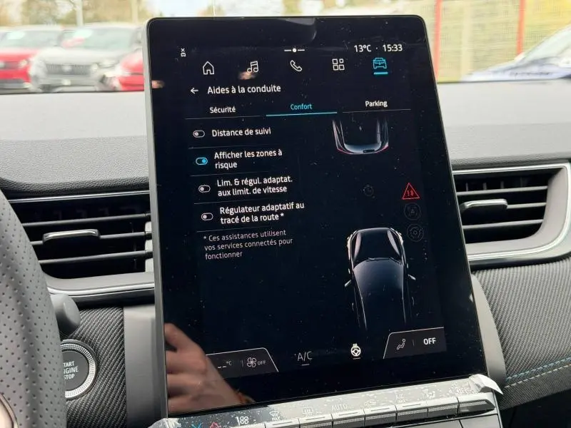 Vue rapprochée de l’écran tactile central affichant les aides à la conduite du Renault Captur blanc nacré/noir étoile.