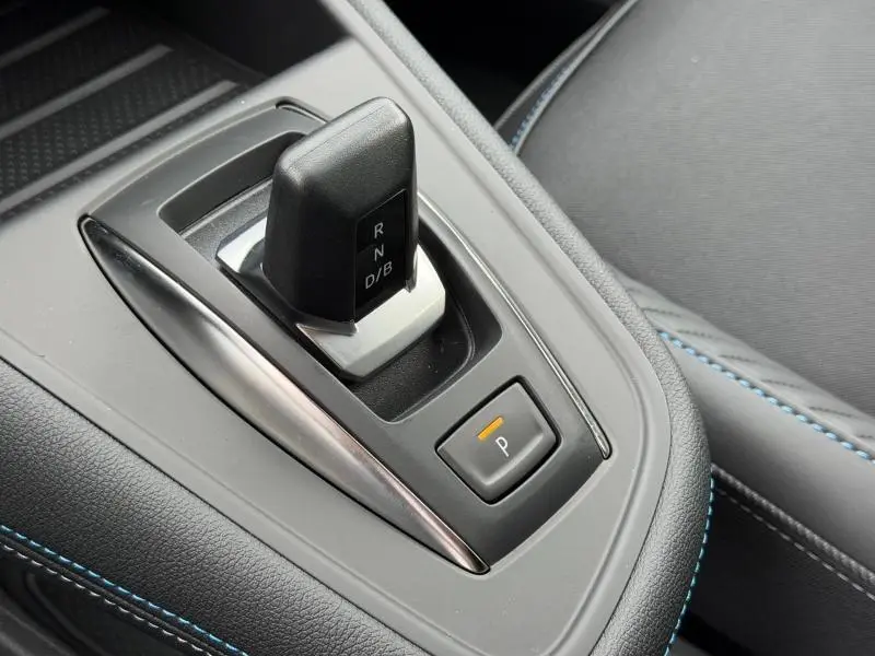 Gros plan sur la commande de boîte automatique noire et argentée dans l’habitacle du Renault Captur blanc nacré.