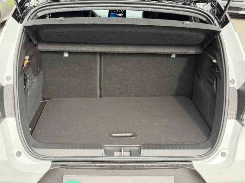 Coffre ouvert vu de l'arrière d'un Renault Captur blanc nacré/noir, montrant l'espace de rangement vide et la tablette arrière.