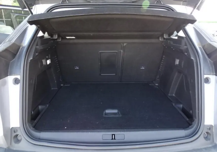 Coffre ouvert vu de l'arrière d'un Peugeot 3008 gris Artense, montrant l'espace de chargement vide et la tablette cache-bagages.