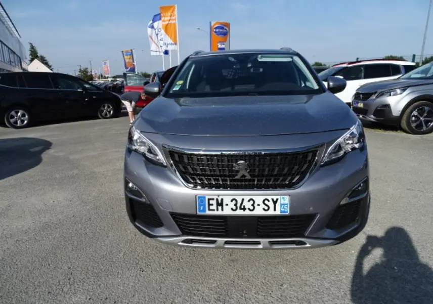Vue frontale d'un Peugeot 3008 gris Artense métallisé, avec calandre noire et plaques d'immatriculation visibles.