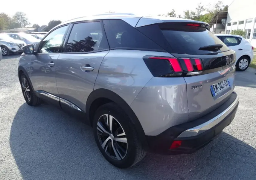 Peugeot 3008 gris Artense en 3/4 arrière droit, avec barres de toit aluminium et feux arrière à griffes rouges.