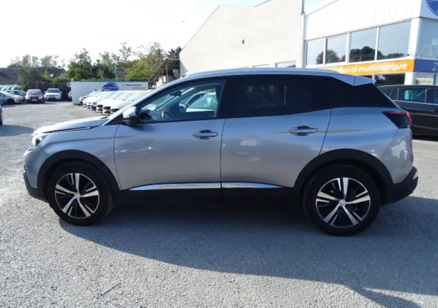 Profil droit du Peugeot 3008 gris Artense avec toit noir et barres de toit en aluminium visibles sur parking.