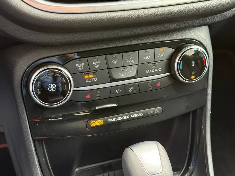 Vue rapprochée de la console centrale noire du Ford Puma 2024, montrant les commandes de climatisation et chauffage.