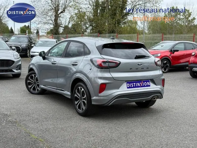 Vue 3/4 arrière droite d'une Ford Puma 2024 grise finition ST-Line avec détails sportifs et feux arrière LED.