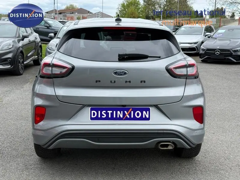 Vue arrière d'une Ford Puma 1.0 EcoBoost 155ch mHEV ST-Line 2024 gris métallisé avec feux distinctifs et sortie d'échappement chromée.